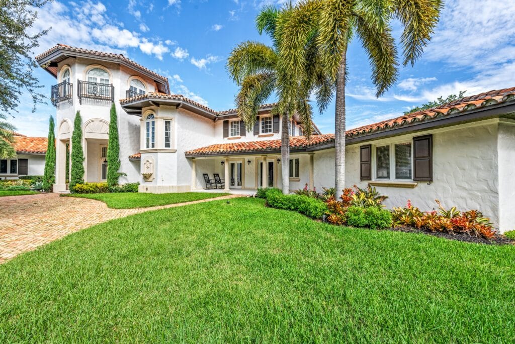 Low maintenance landscaping in Florida with palm trees, manicured lawn, and mulch beds in front of Cape Coral home.